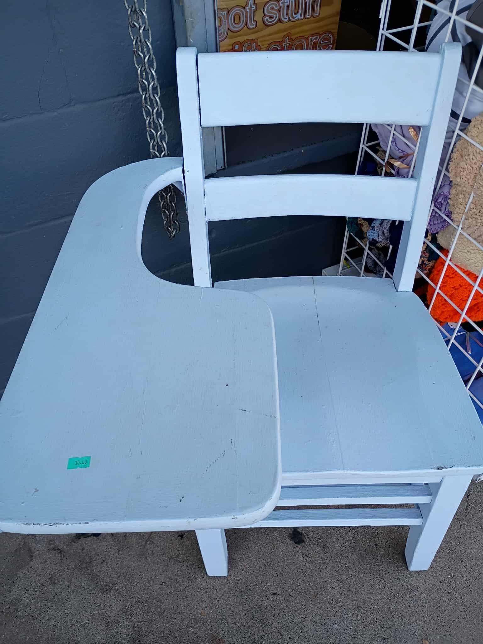 A child's light blue wooden school desk and chair. The desk is attached to the chair's side.