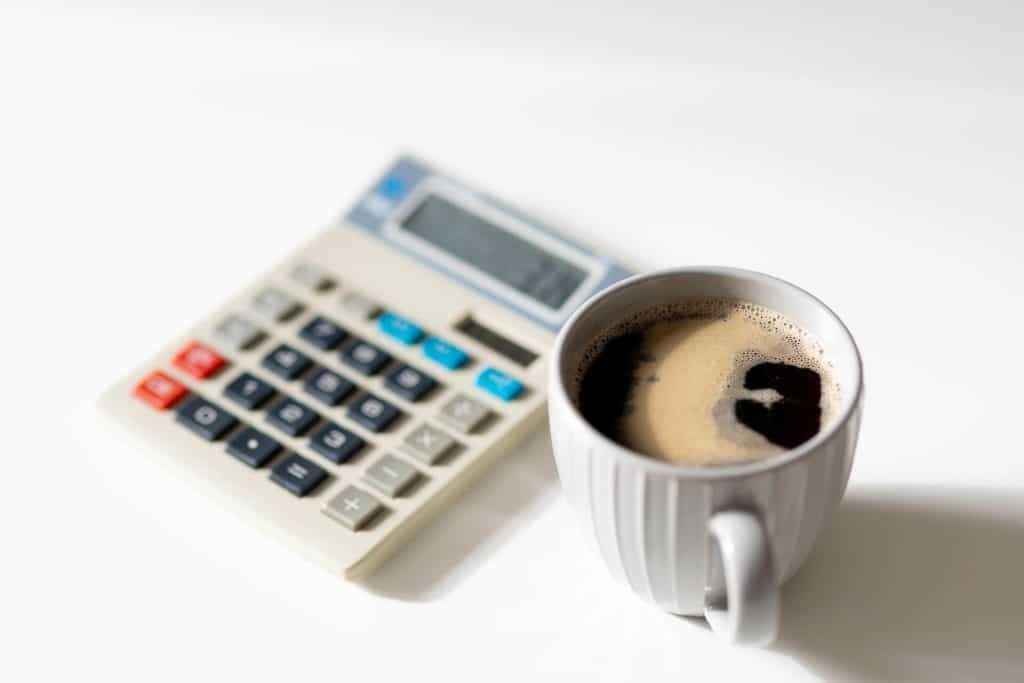 Calculator and cup of coffee on a white surface.