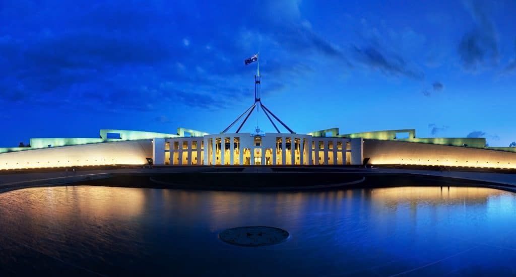 Parliament House, Canberra, Australia at dusk; lights reflect on the water.