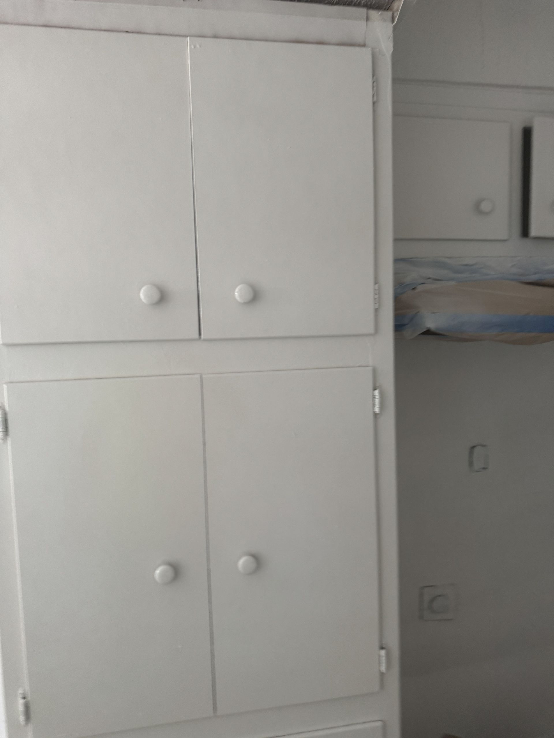 White built-in cabinet with four doors in a small bedroom beside an open bunk bed alcove