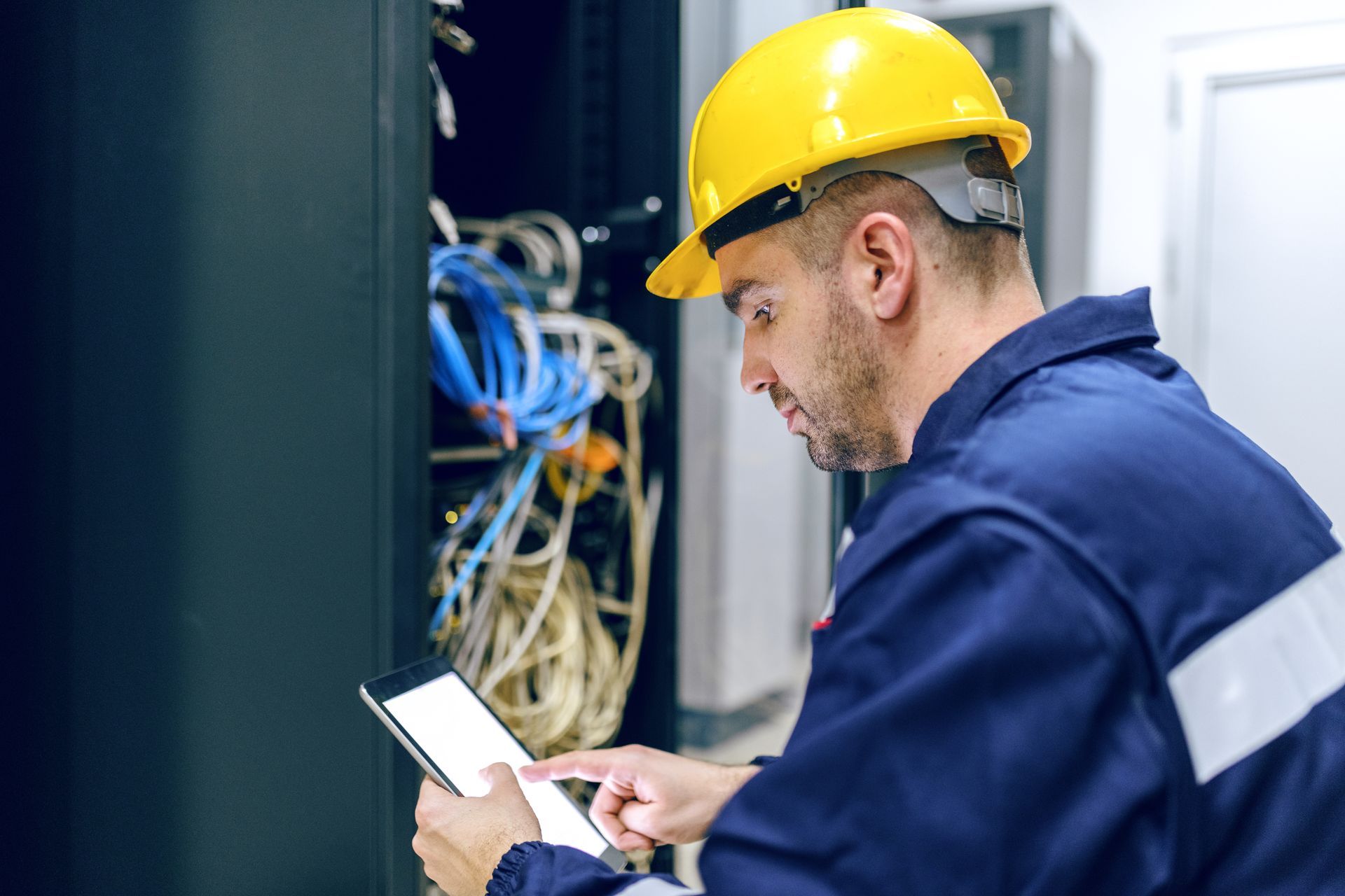 Technician adjusting cables on a network panel inside an equipment cabinet.