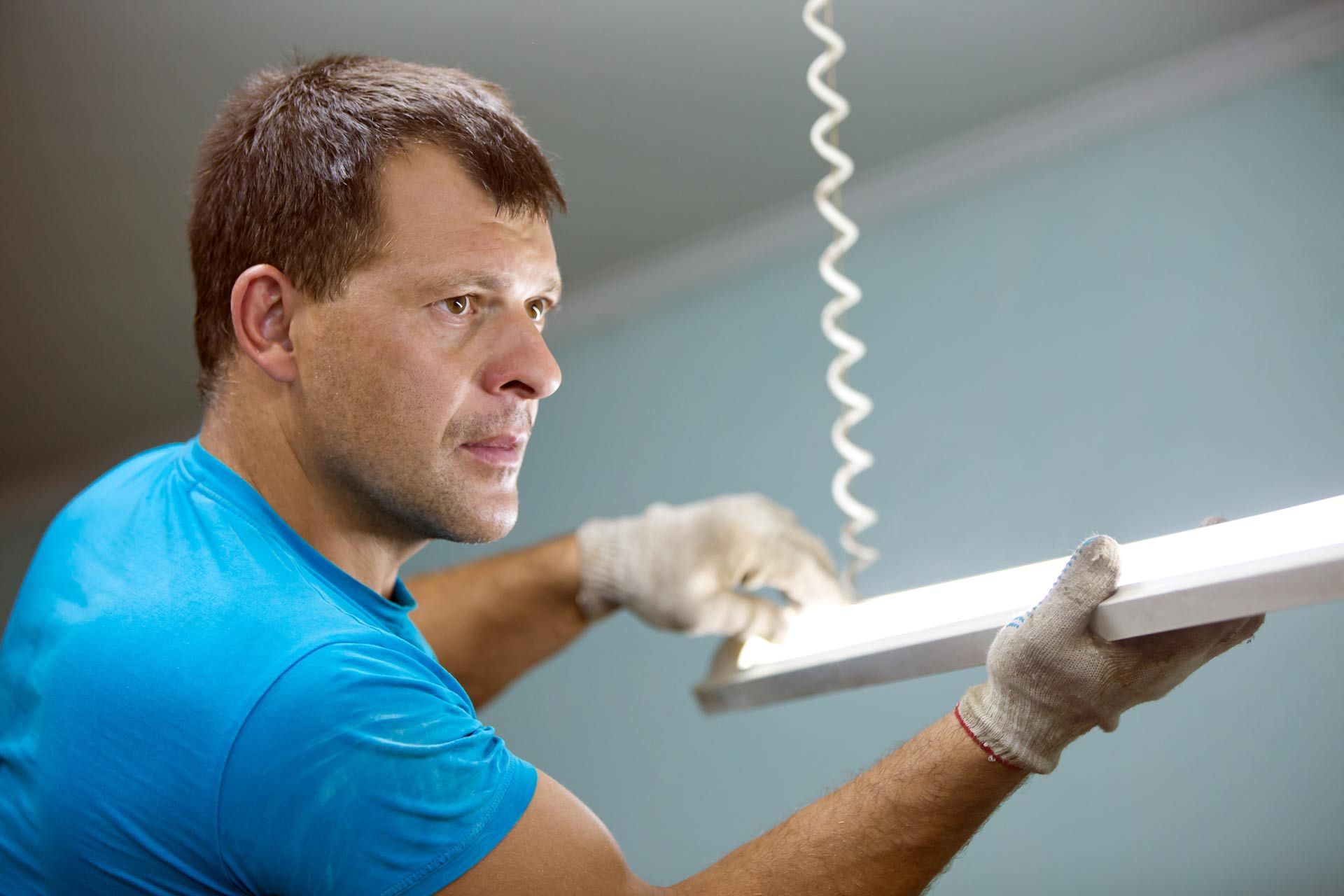 A professional sparky is installing a ceiling fluorescent lamp.