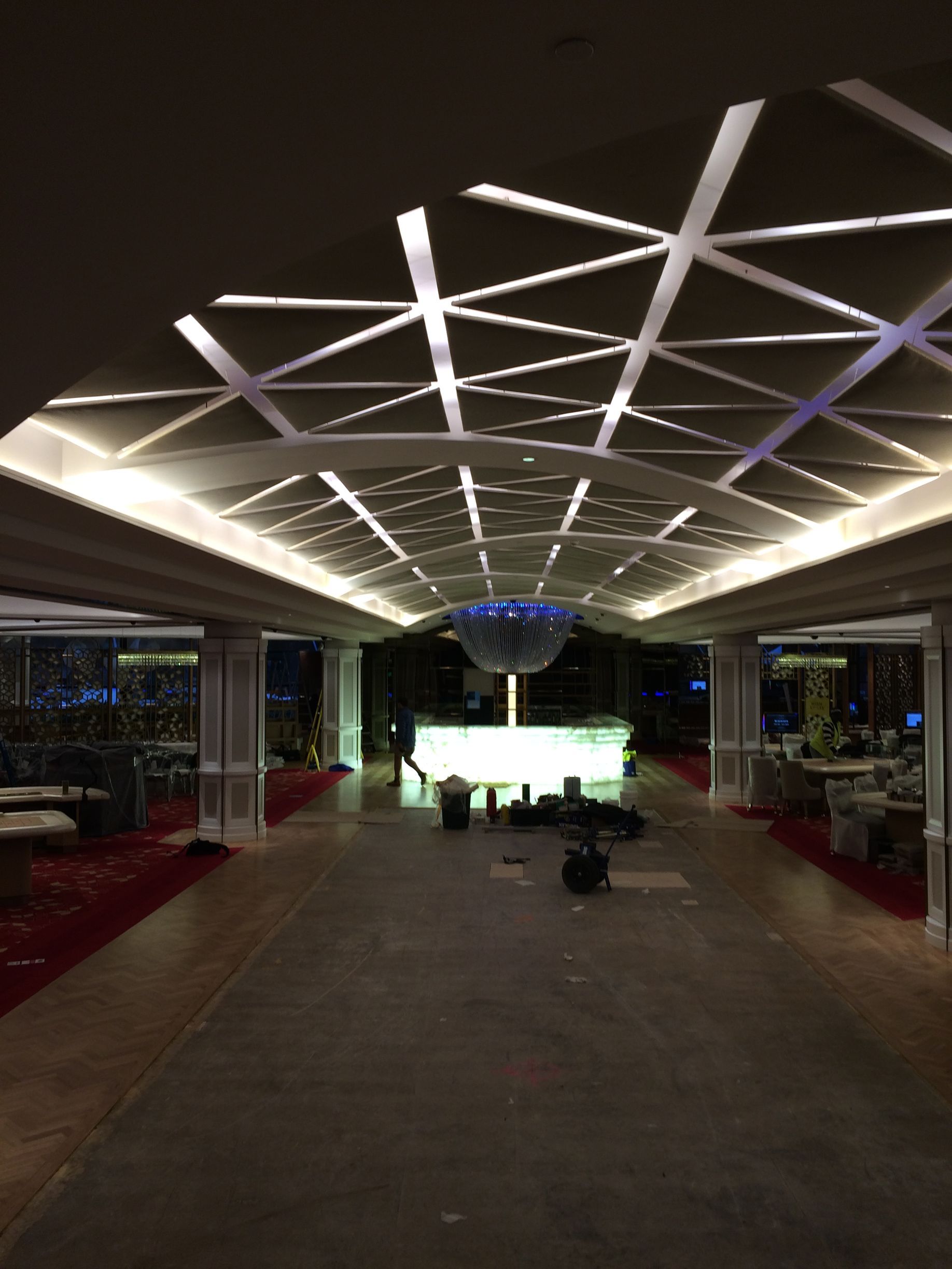 Modern airport terminal walkway with geometric ceiling lights and a bright entrance ahead