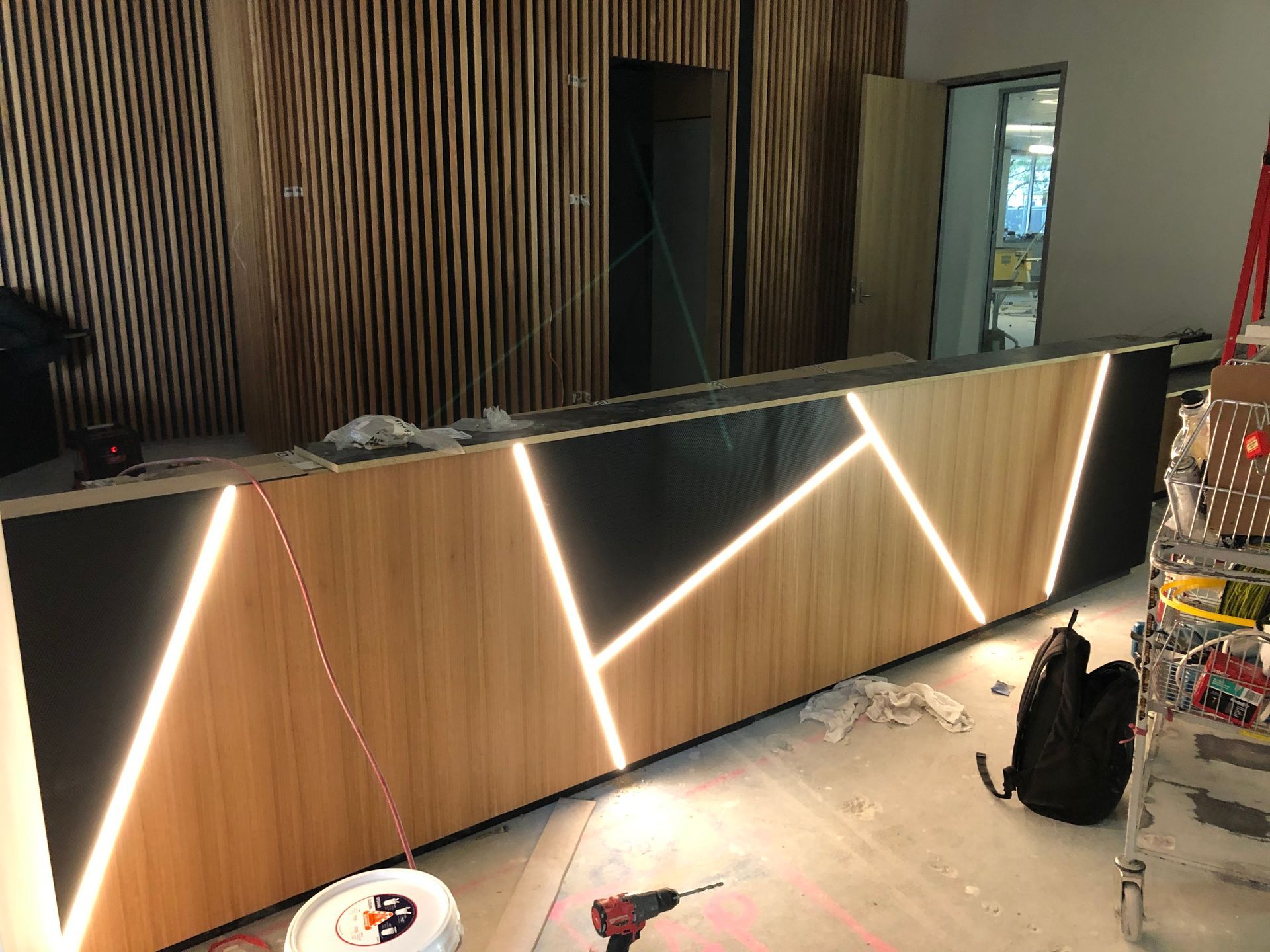 Modern reception desk with wood panels and zigzag LED lighting in a dim interior room