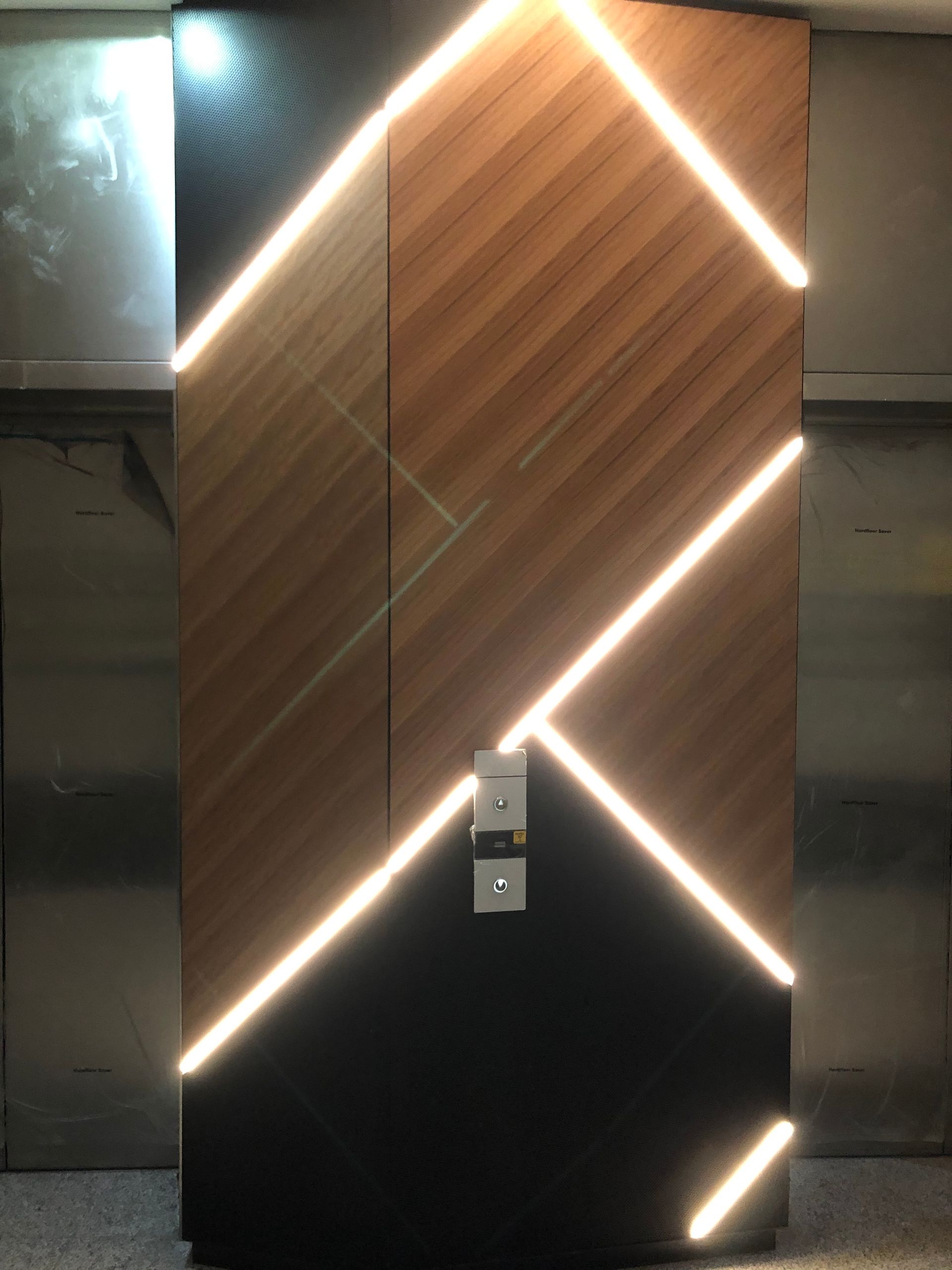 Wood-paneled wall with diagonal LED light strips and a small wall fixture in the center