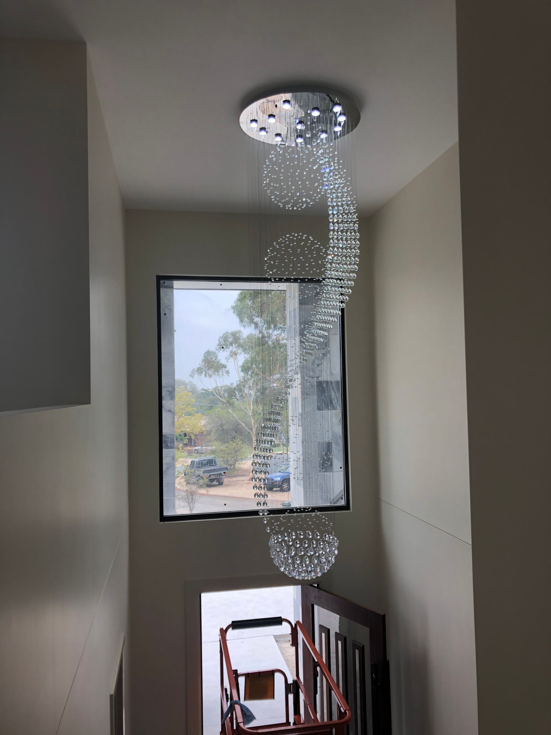 Water pouring from a ceiling light fixture onto a stairwell landing by a window
