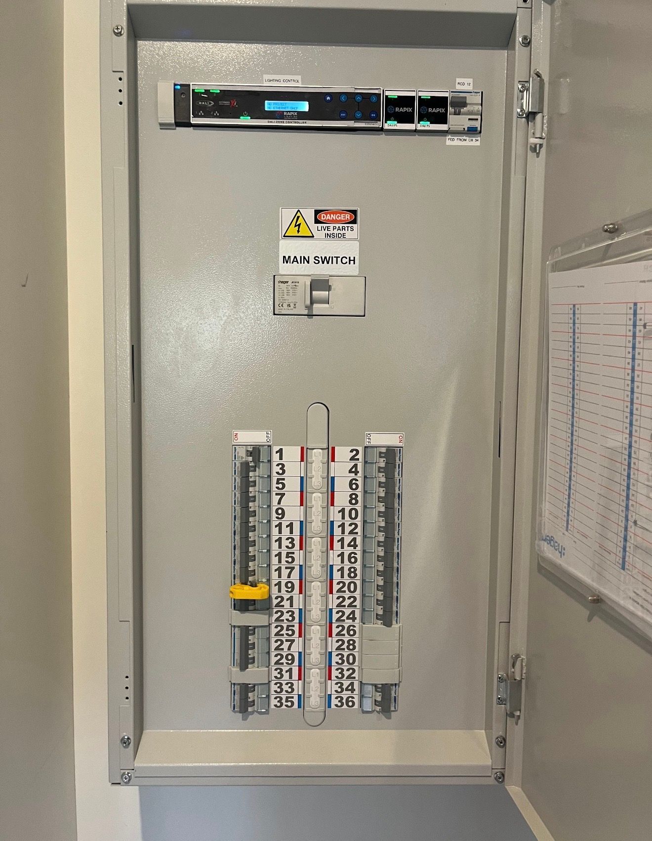 Open electrical breaker panel with labeled circuits and warning sticker on the door