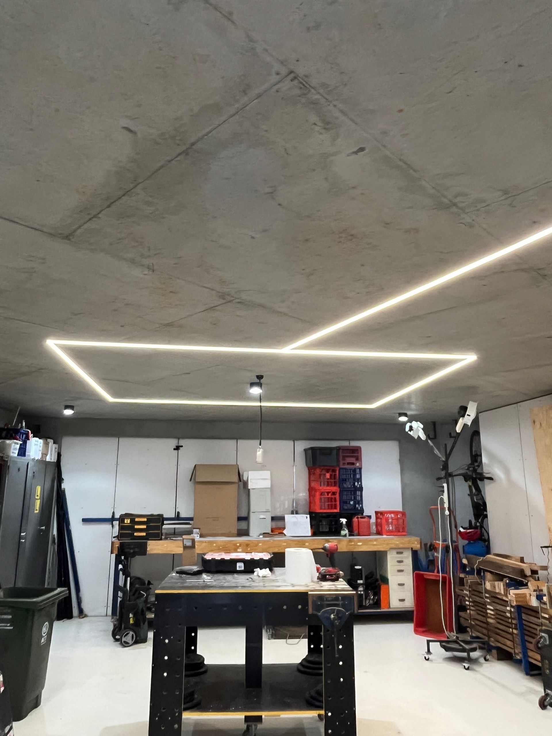 Modern garage workshop with LED ceiling lights, workbench, shelves, and tools against concrete walls