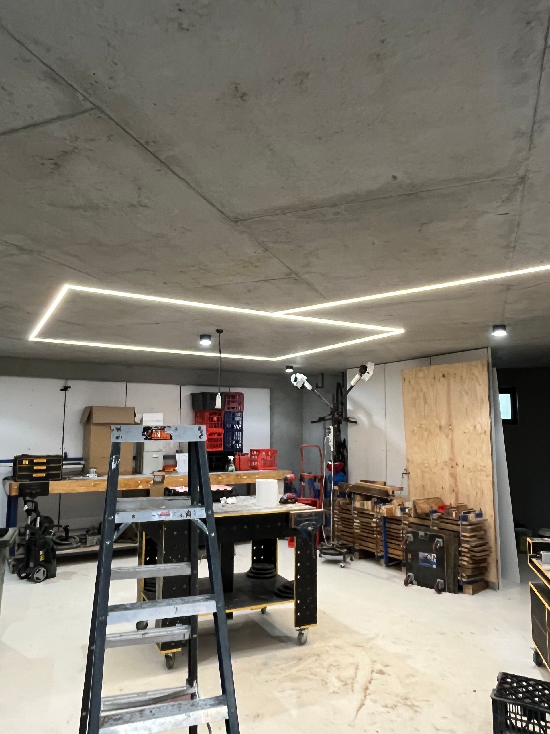 Garage workshop with ladder, workbench, shelves, and LED ceiling lights