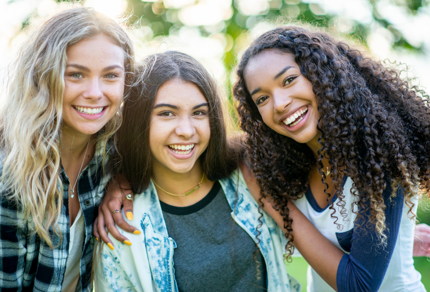 Three teenage girls with their arms around each other.