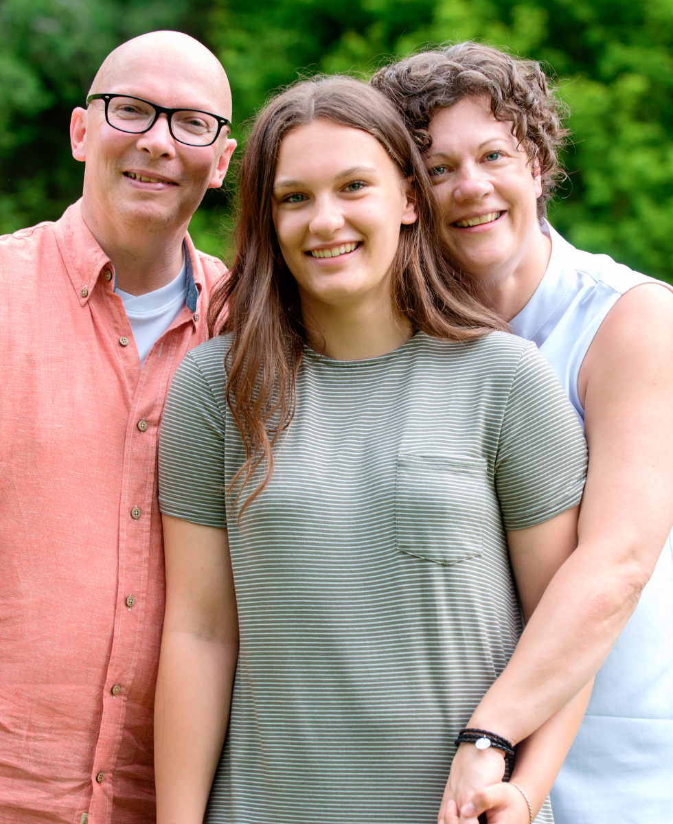 A man and two women are posing for a picture with a girl.