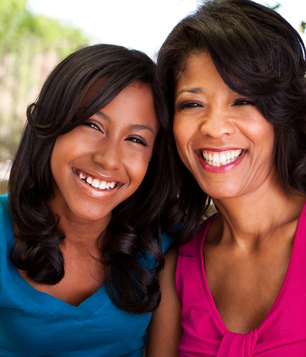 Two women are posing for a picture and smiling for the camera
