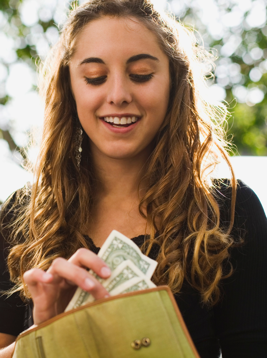 A woman is taking money out of her wallet and smiling