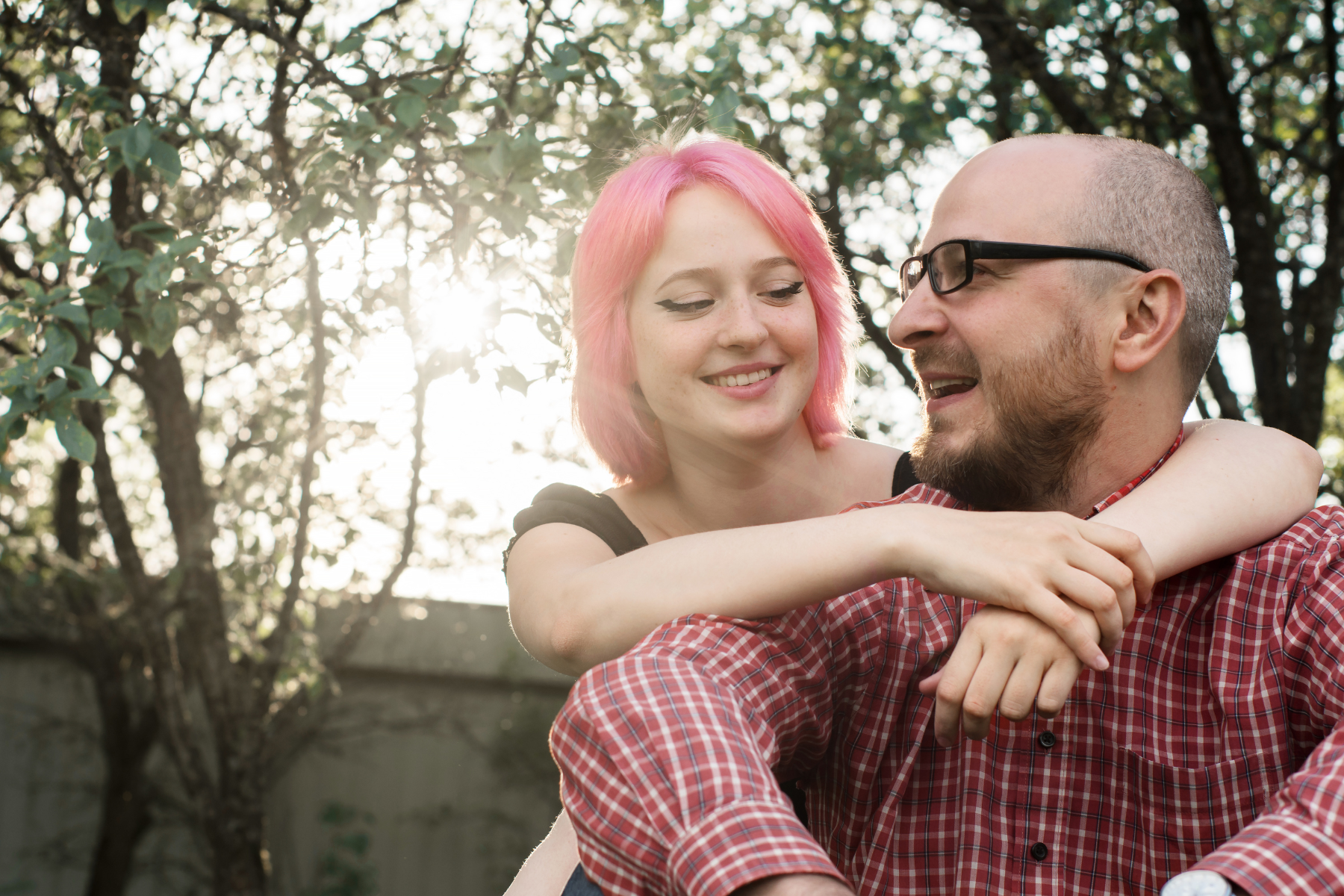 A man is carrying a woman on his shoulders in a park.