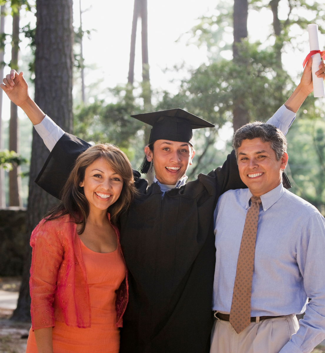 A man in a graduation cap and gown stands with two other people