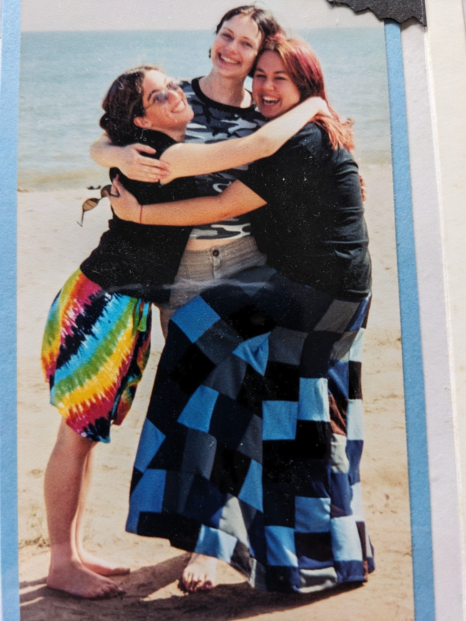 A mother hugging her teens on a beach