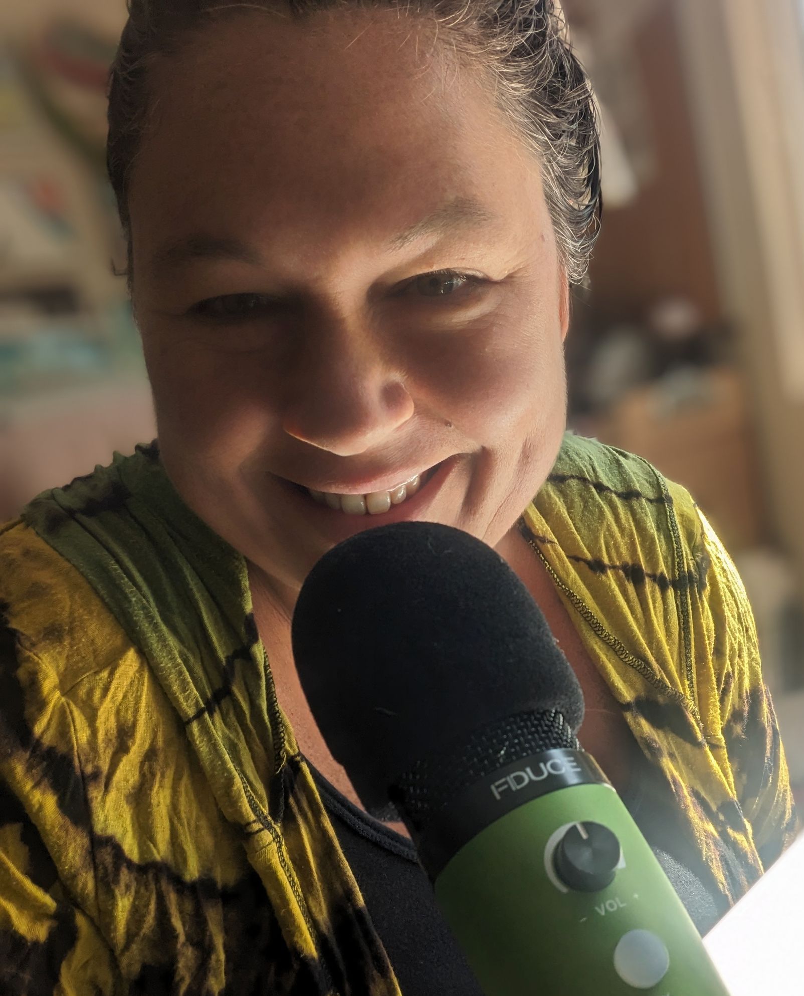 A woman is smiling while holding a green microphone