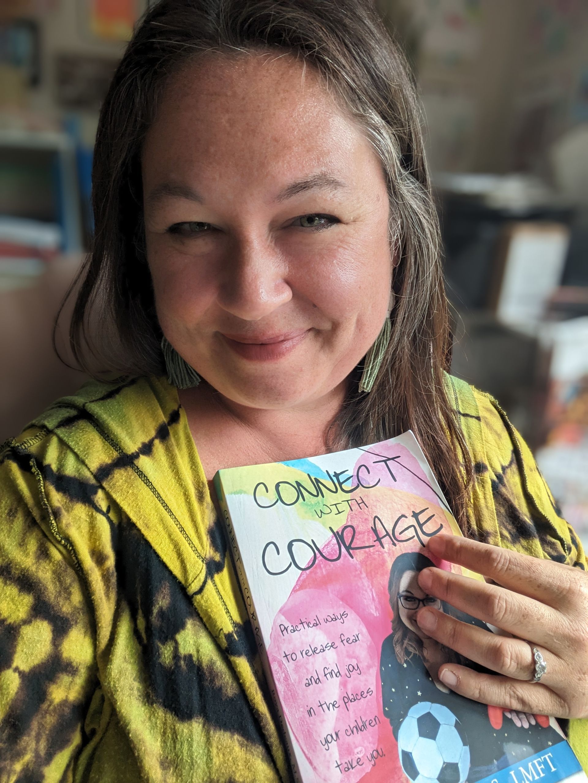 A woman is holding a book titled connect to courage.