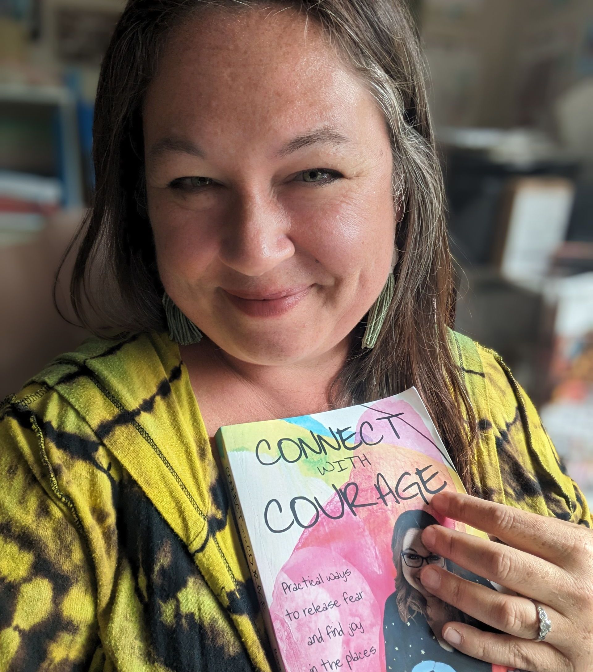 A woman is holding a book titled connect with courage.