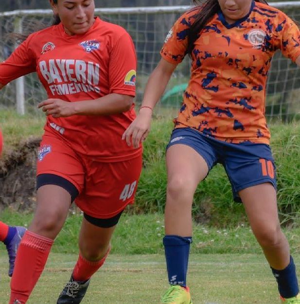 Two women are playing soccer on a field and one has the number 10 on her shorts.