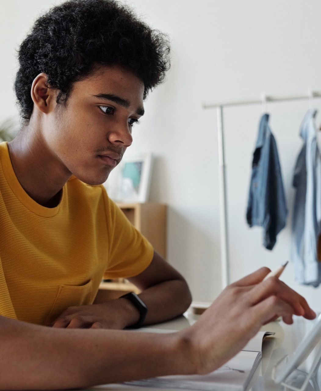 A young man in a yellow shirt is using a tablet computer