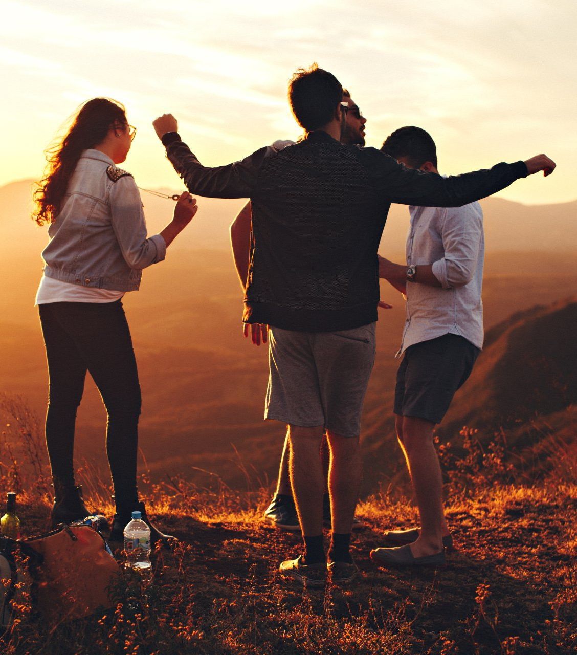 A group of people standing on top of a hill at sunset