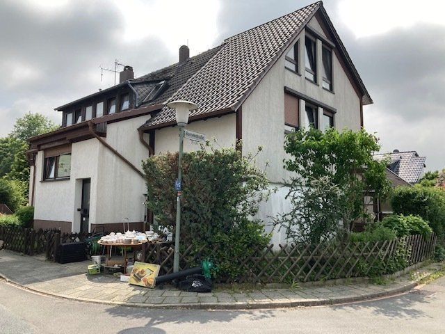 An einer Straßenecke steht ein weißes Haus mit einem braunen Dach.