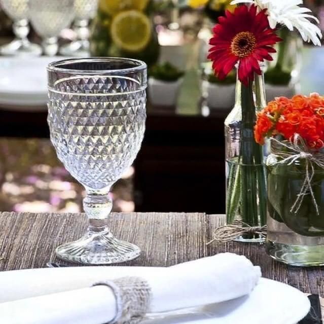 Vaso de agua sobre una mesa de madera, parte de una mesa con flores.