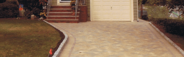 A brick driveway leading to a house with stairs.