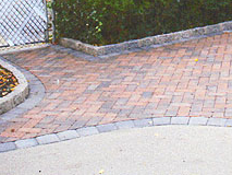 A brick walkway with a chain link fence in the background.