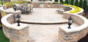 A curved stone wall surrounds a patio with a table and chairs.