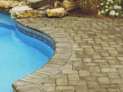 A swimming pool with a brick patio around it