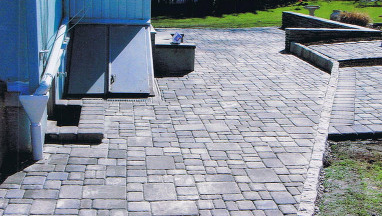 A brick walkway leading to a blue house