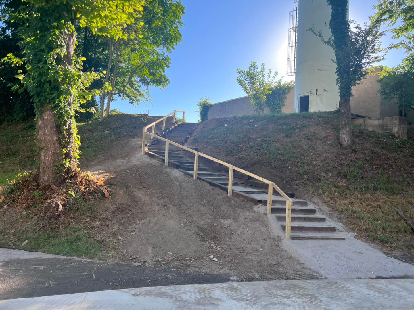 A set of stairs going up a hill with a wooden railing