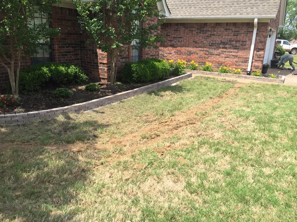 A brick house with a lush green lawn in front of it.
