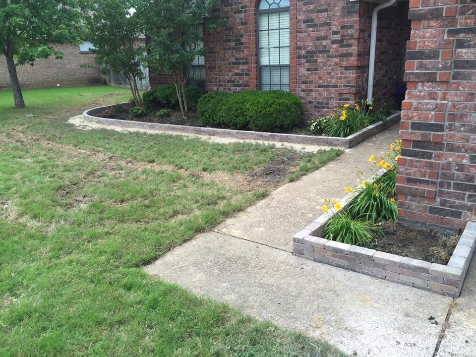 A brick house with a sidewalk and planters in front of it.