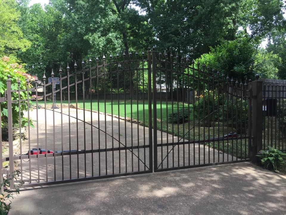 A wrought iron gate is open to a driveway