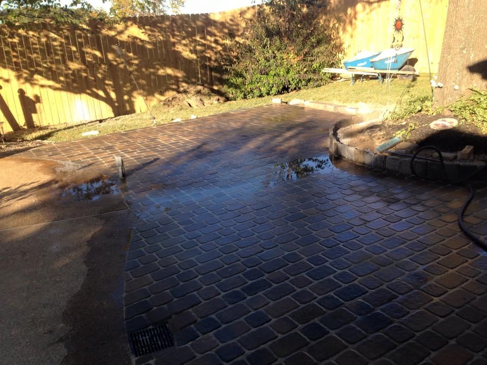 A brick driveway is being cleaned with a pressure washer.