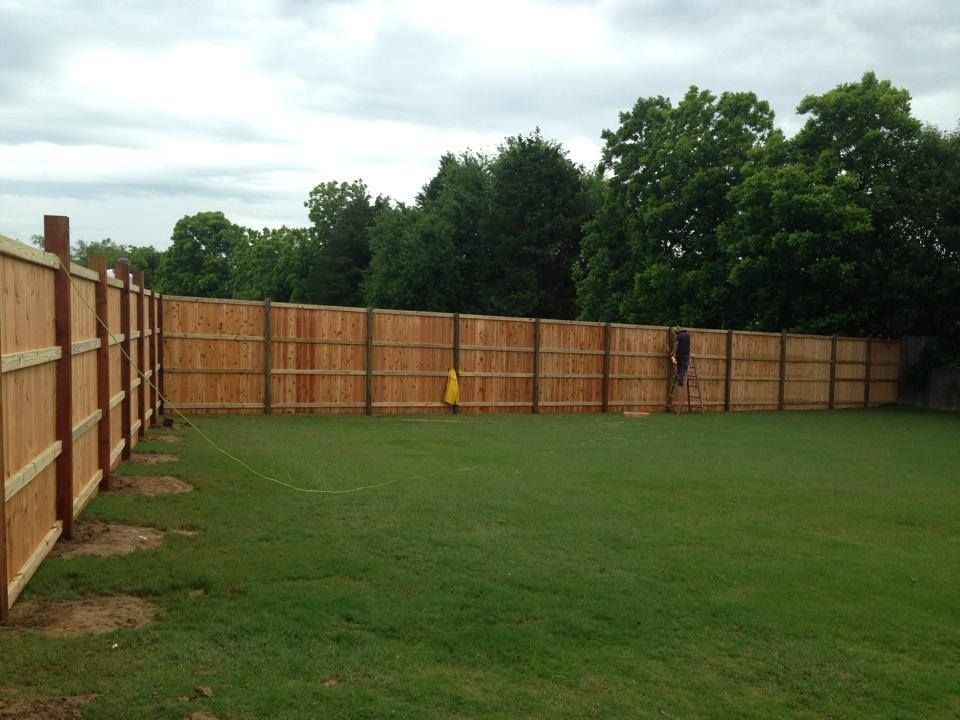 A wooden fence surrounds a lush green field