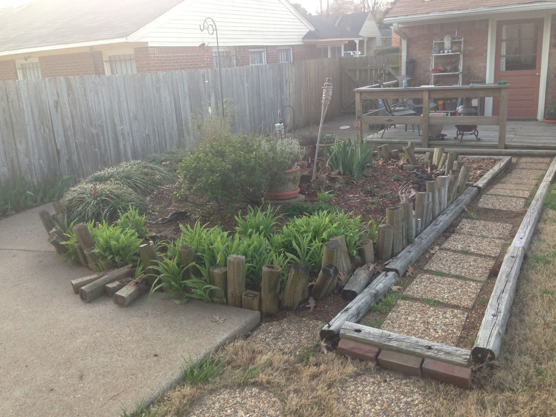 A garden with a wooden fence and a walkway in front of a house.