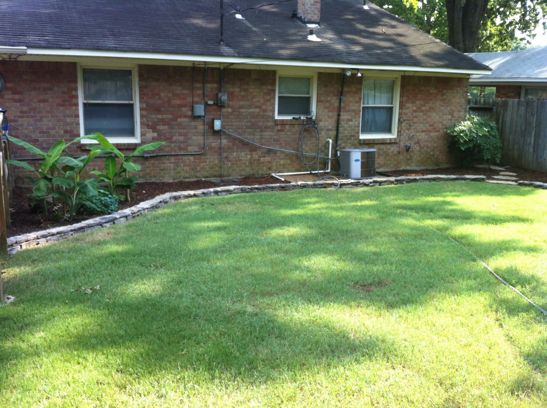A brick house with a lush green lawn in front of it.