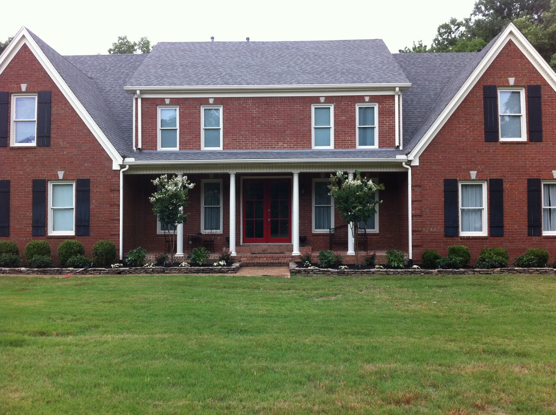 A large brick house with black shutters on the windows