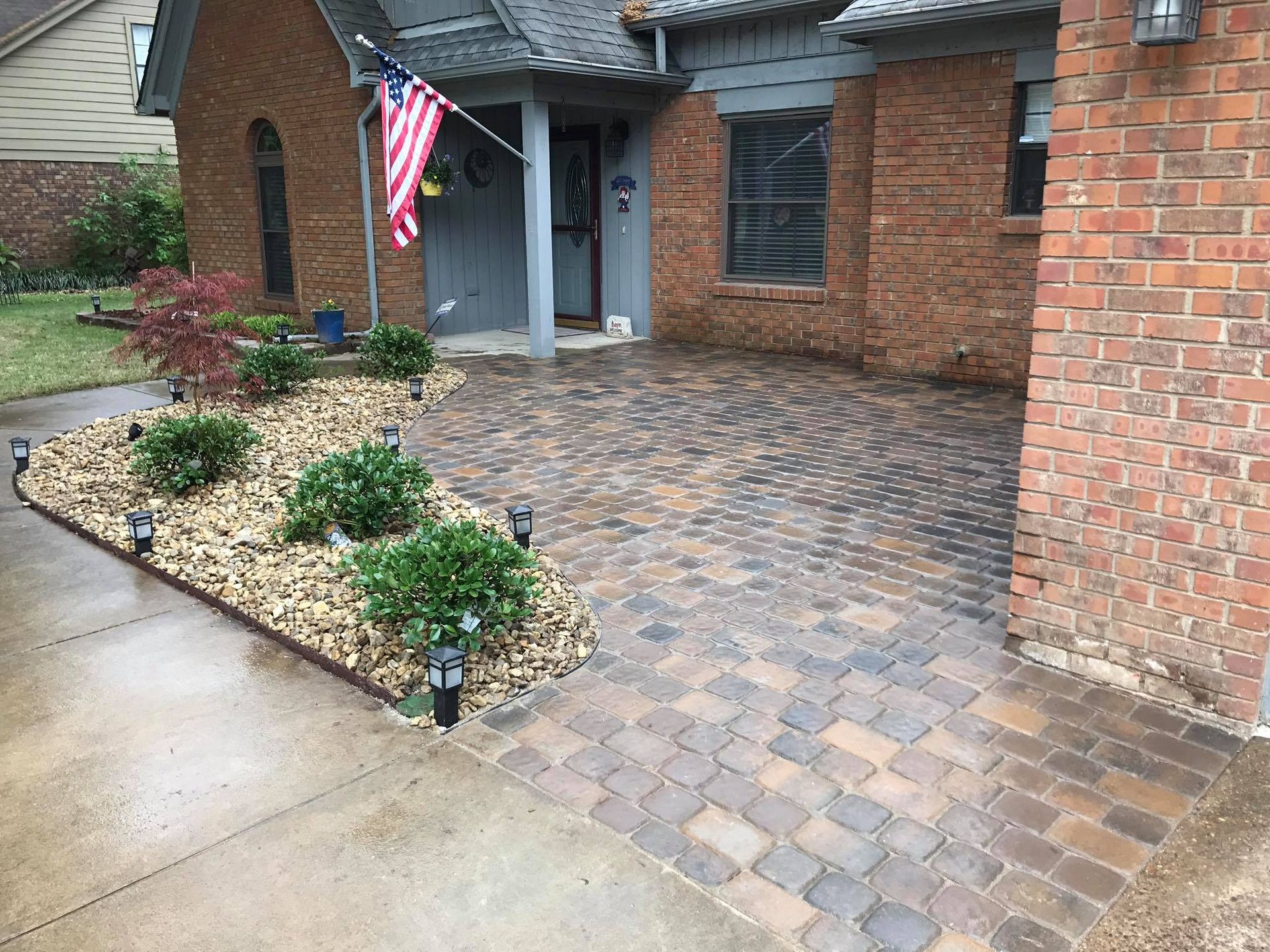 A brick house with a brick driveway in front of it.