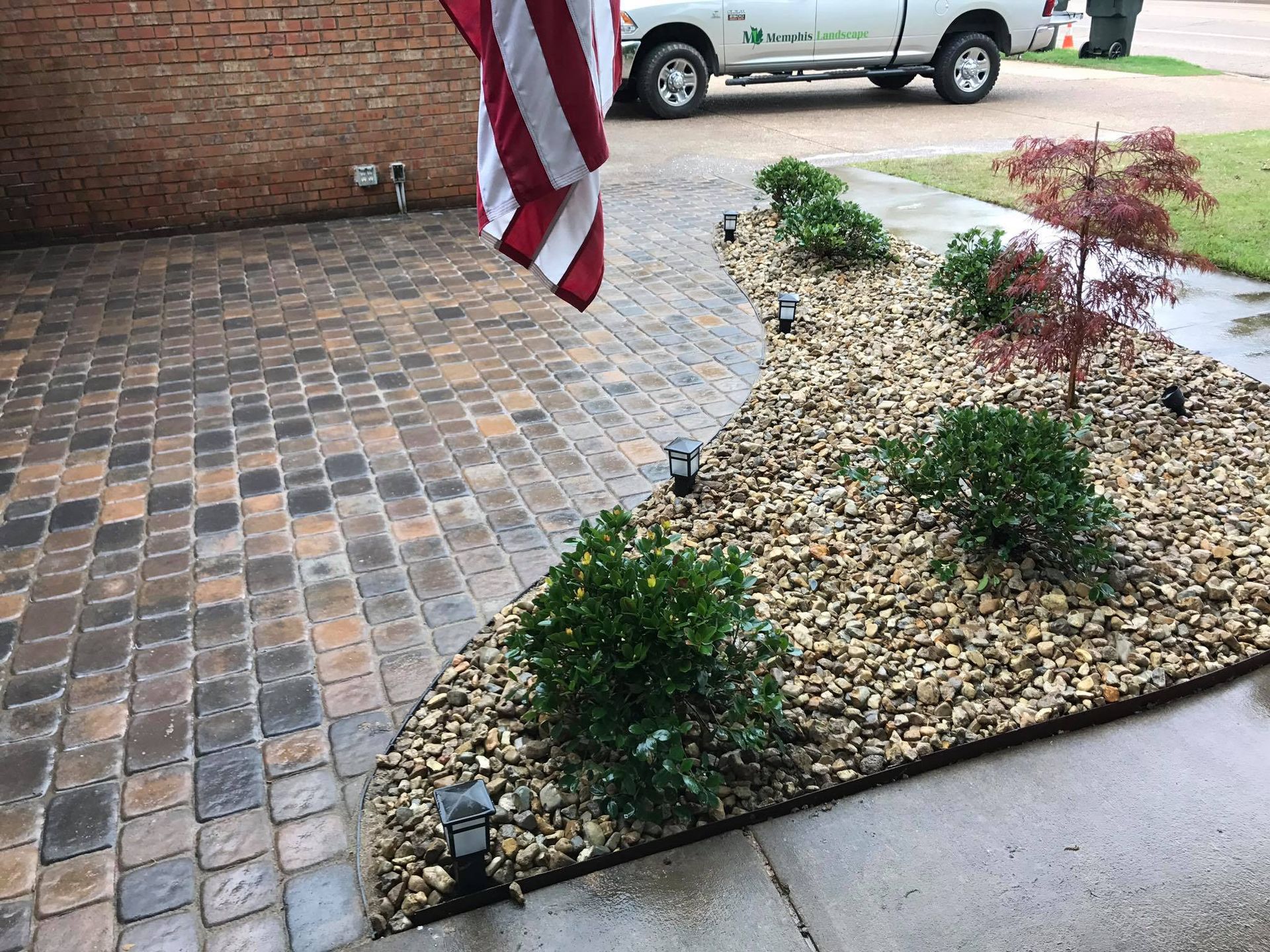 A white truck is parked in front of a brick driveway.