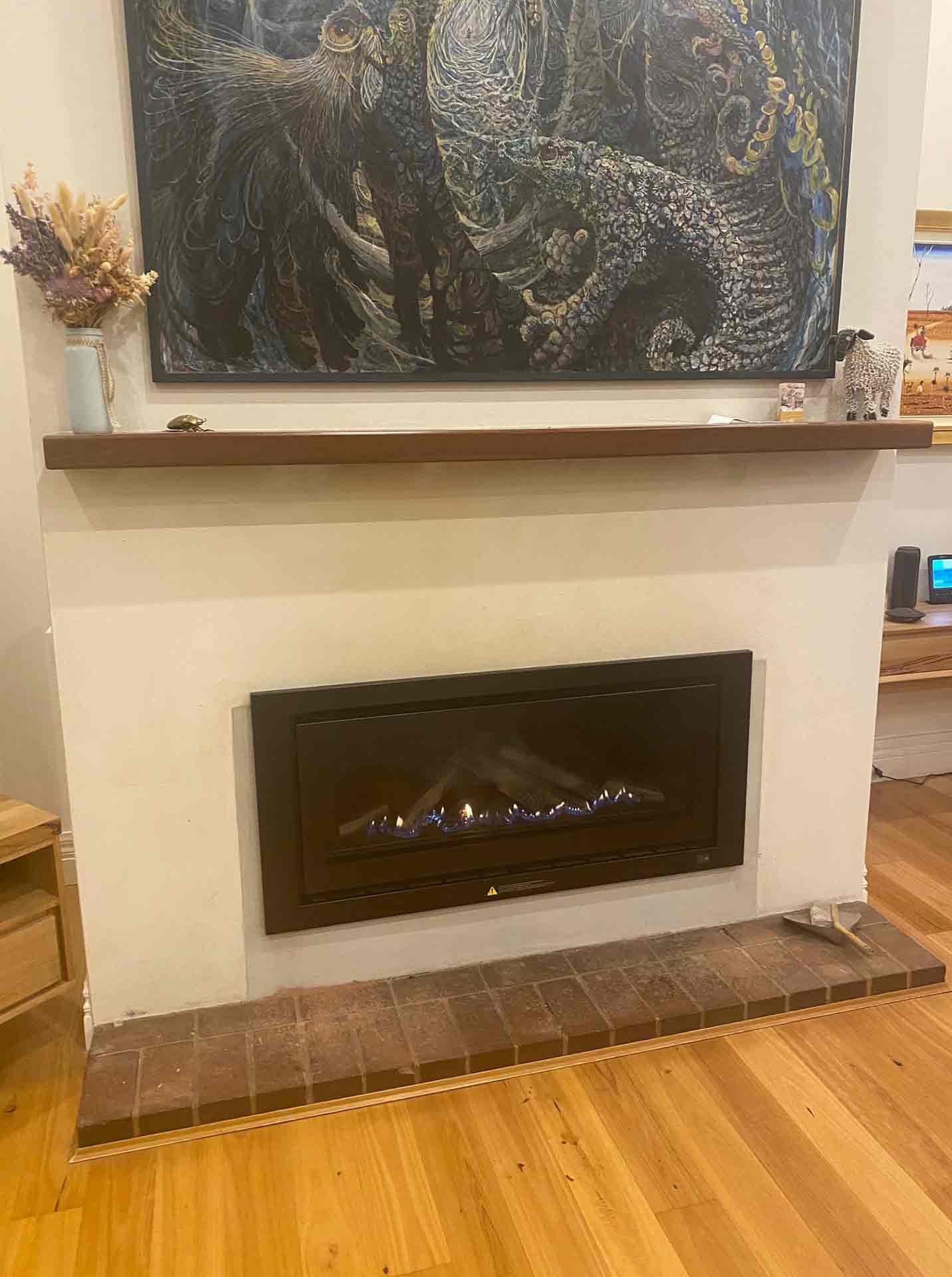 A Fireplace In A Living Room With A Painting On The Wall Above It — PalmAir Heating & Cooling Specialists In Wagga Wagga, NSW