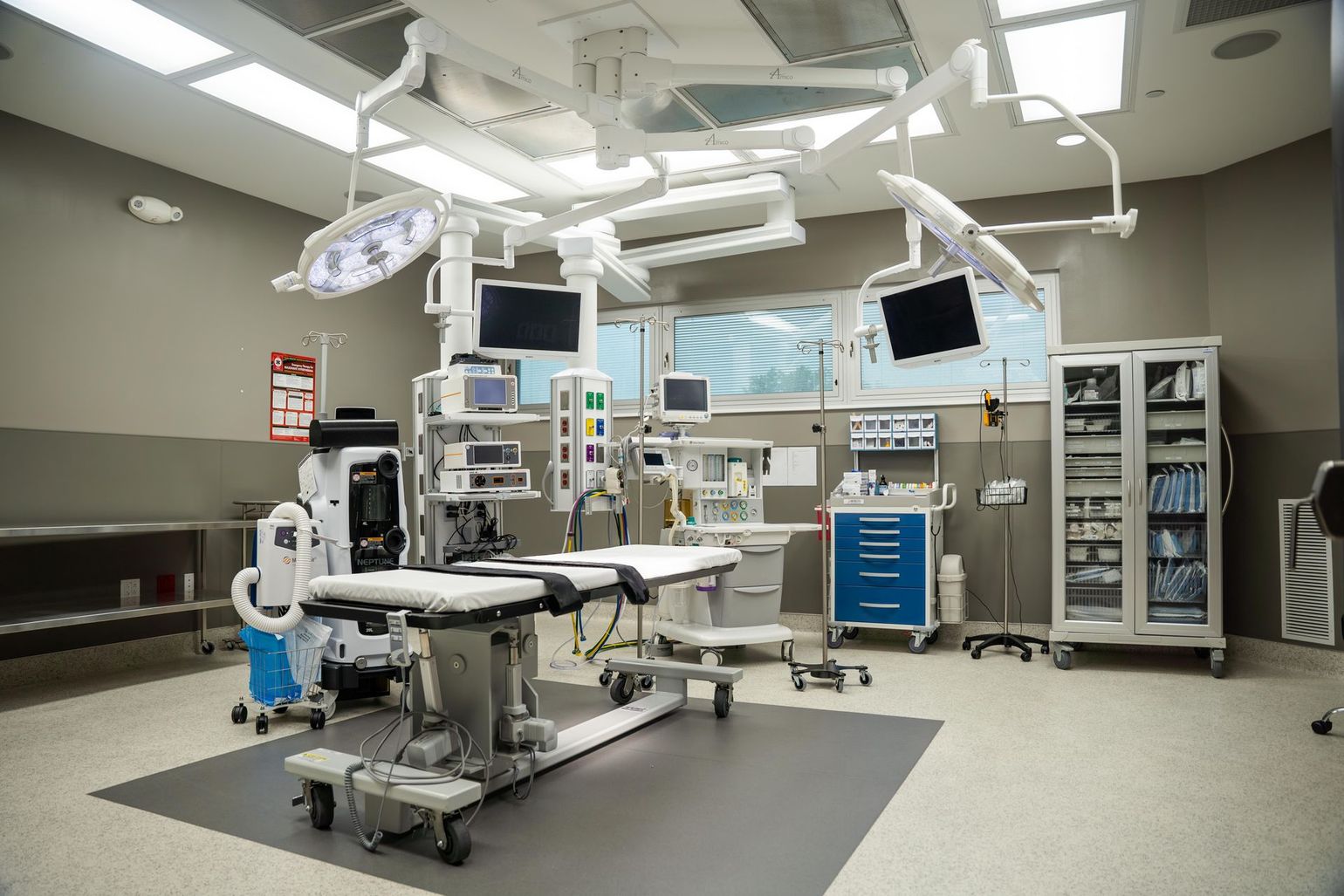 an empty operating room in a hospital with a bed and lots of medical equipment .