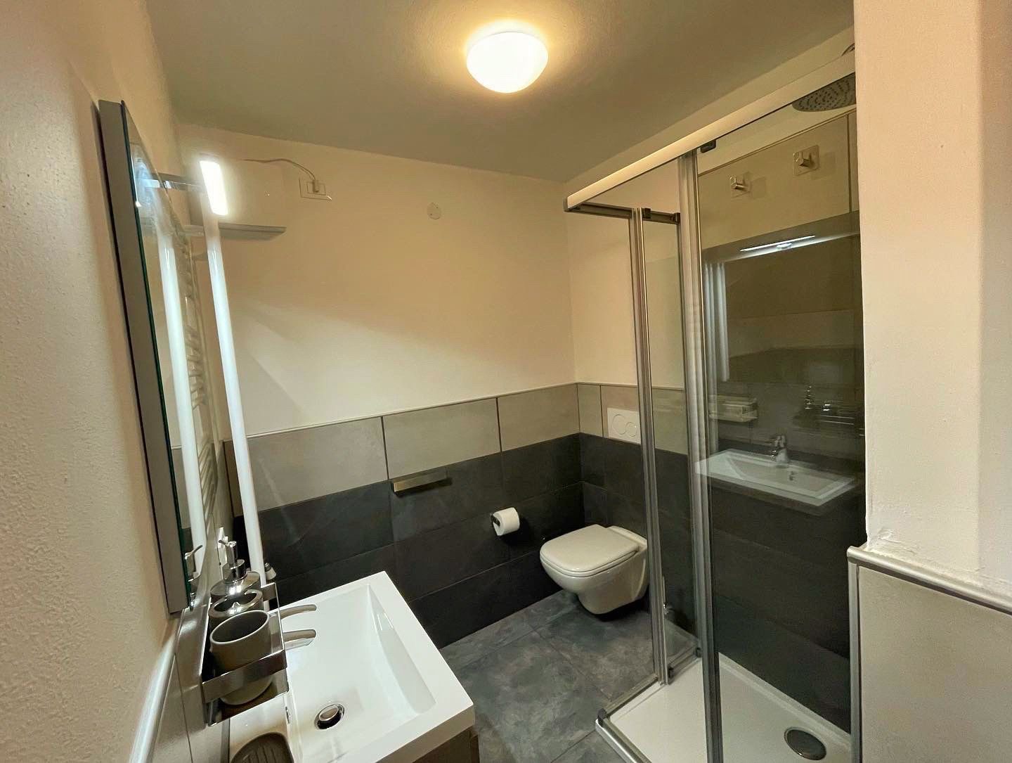 Un bagno con lavandino, water, doccia e specchio.