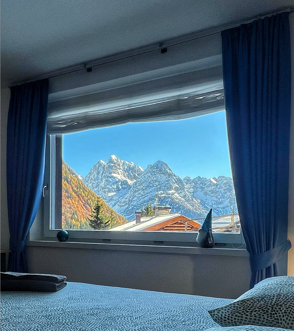 Una camera da letto con un letto e una finestra con le montagne sullo sfondo