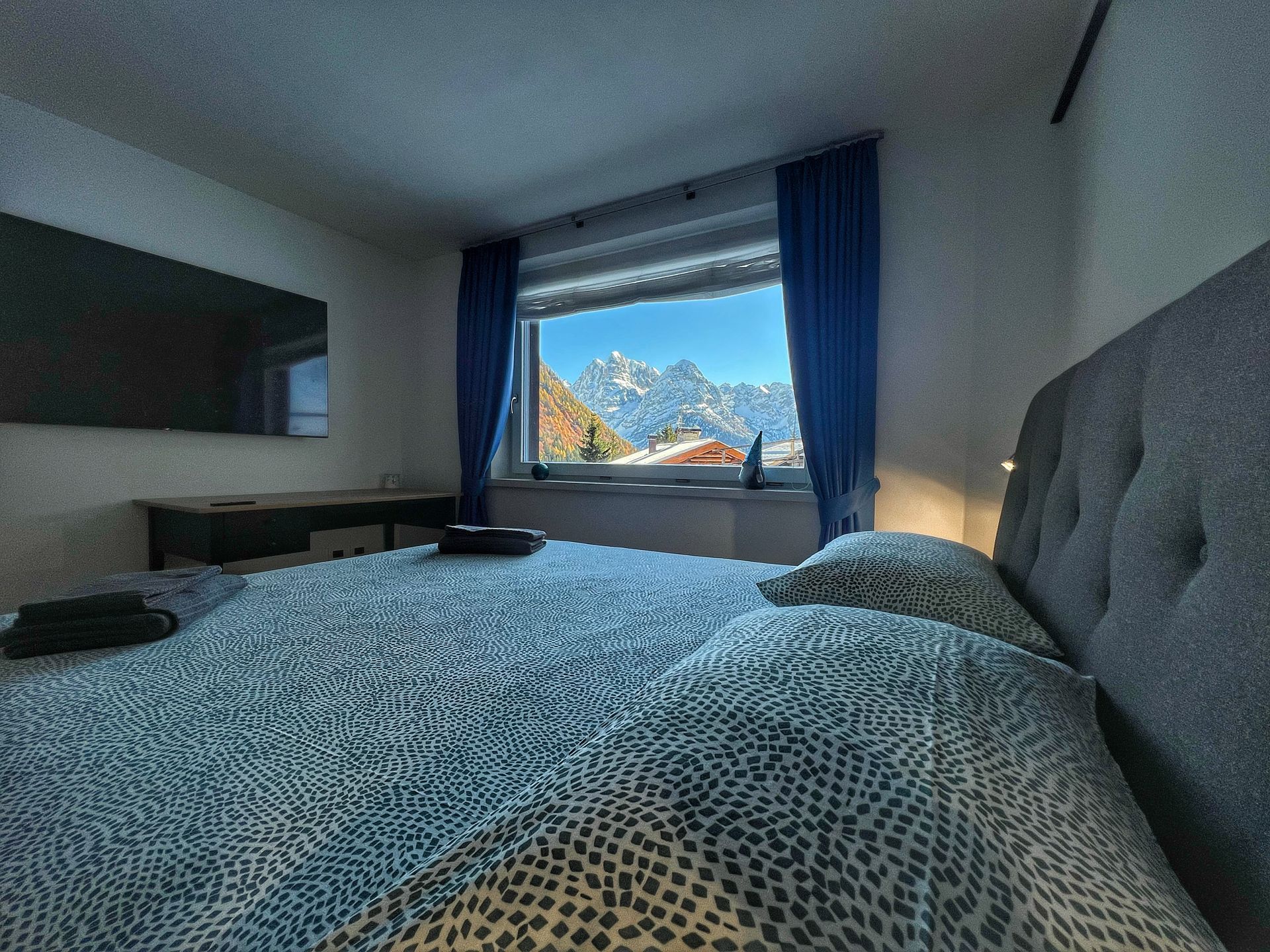 Una camera da letto con letto, televisione, scrivania e finestra.