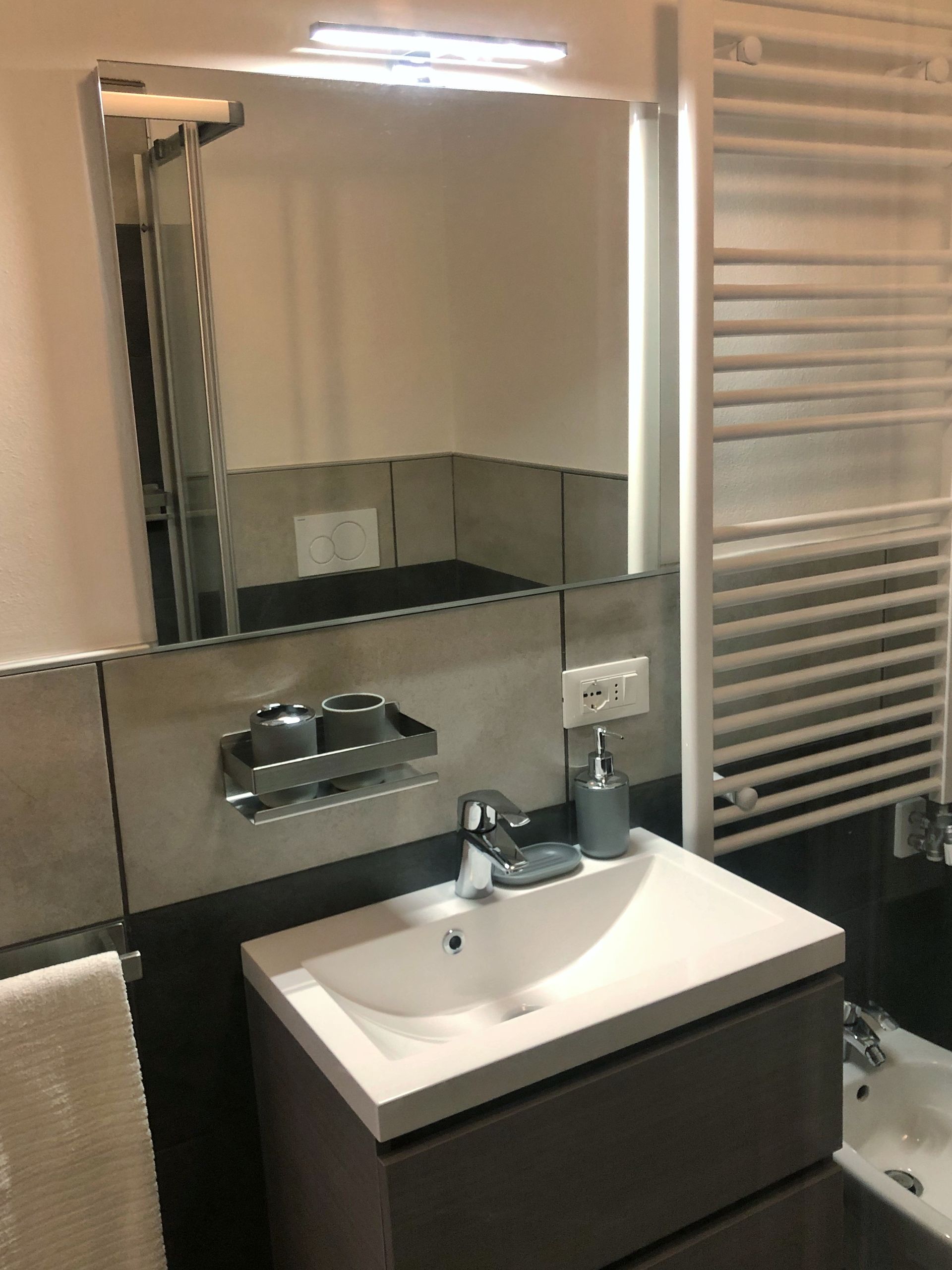 Un bagno con lavandino, specchio e portasciugamani